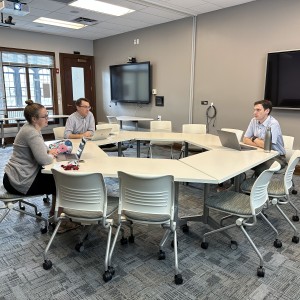 three individuals talking in a classroom