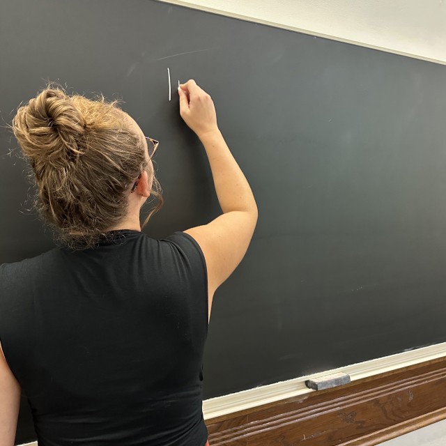 student writing on blackboard